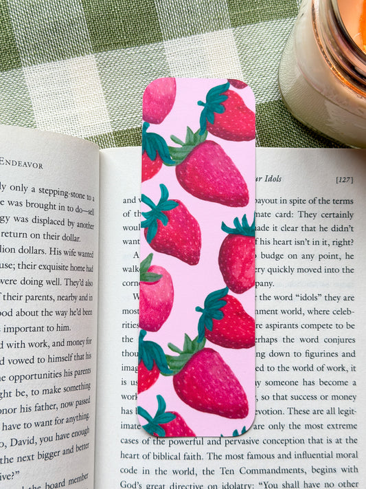 Strawberry patterned bookmark on an open book with a candle in the background