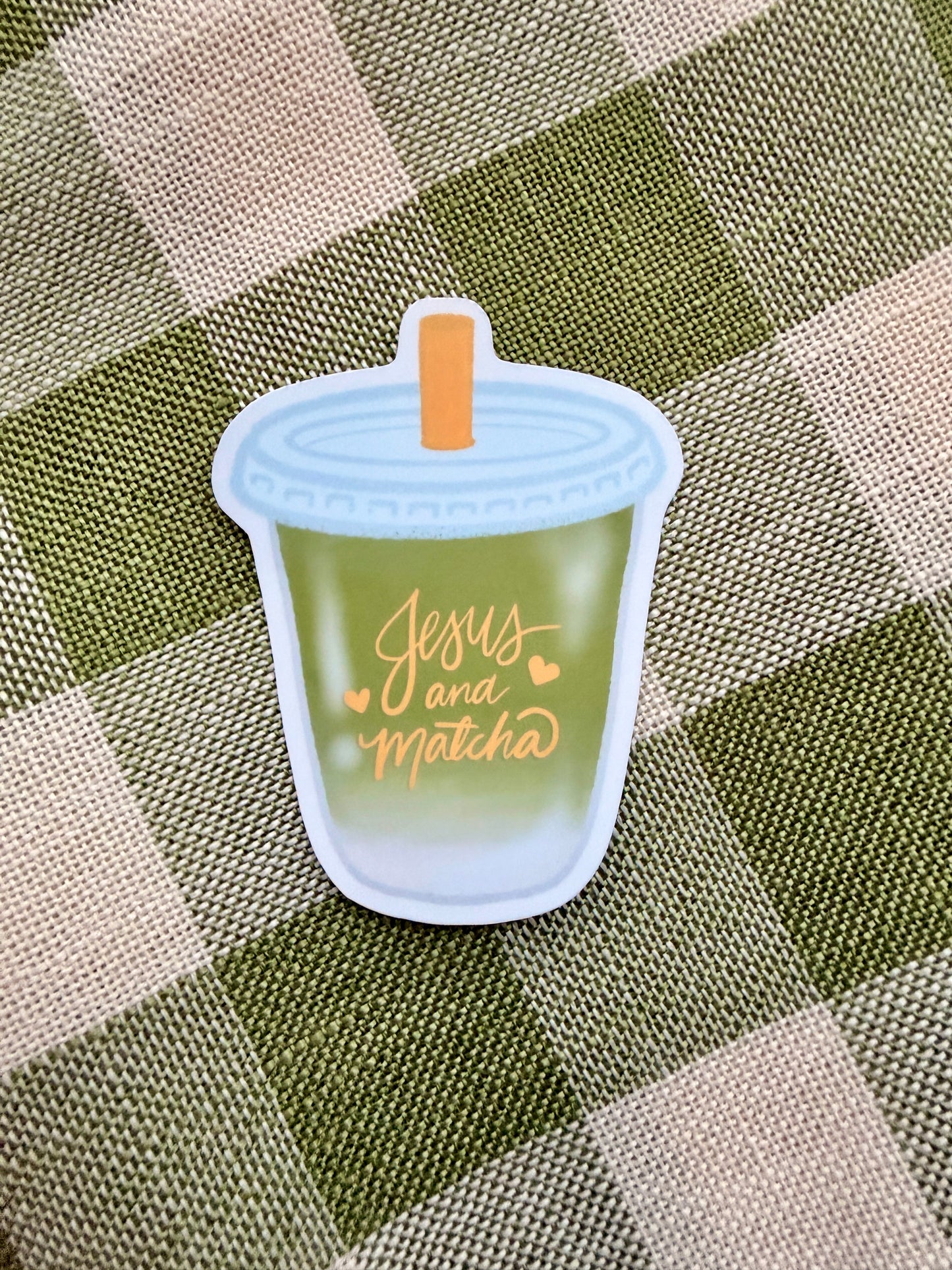 Jesus and Matcha sticker featuring a green cup design with orange text on a checkered background.
